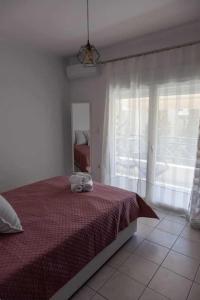 Un dormitorio con una cama con una manta roja y una ventana. en Photo gallery apartment, en Kavala