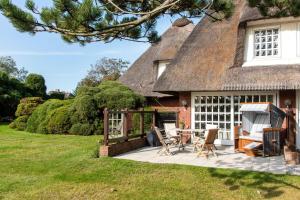 a patio with a table and chairs in front of a thatched house at Devenkamp in Kampen