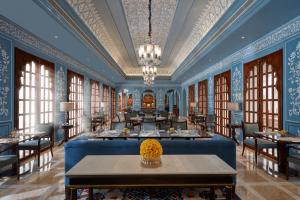 a dining room with blue walls and tables and windows at Mementos by ITC Hotels Jaipur in Jaipur
