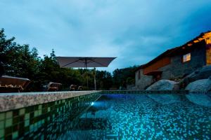 a swimming pool with an umbrella next to a house at Casa Ponte de Espindo in Lousada
