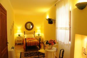 a yellow room with a bed and a mirror at La Casa Di Babbai in Nuchis