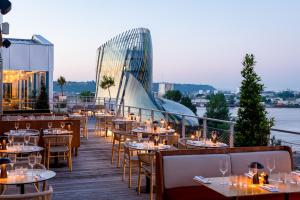 a restaurant with tables and chairs on a deck at Renaissance Bordeaux Hotel in Bordeaux
