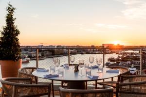 a table on a balcony with a view of the water at Renaissance Bordeaux Hotel in Bordeaux