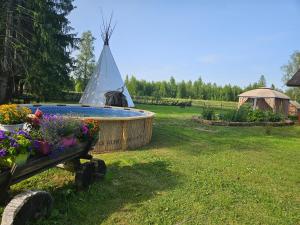 a swimming pool in a yard with flowers and a tent at Kargoja Talu in Saunametsa