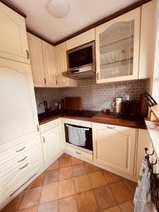 a kitchen with white cabinets and a microwave at Achentalglück in Unterwössen