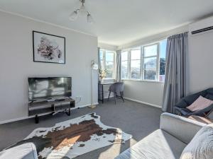 Una sala de estar con un sofá y un televisor. en Classical kiwi holiday home near city center, en Rotorua