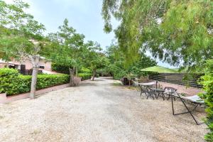 une allée de gravier avec deux bancs et un parasol dans l'établissement Appartamento La Natura, à Capoliveri