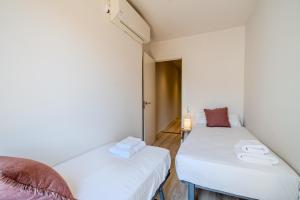 two beds in a small room with white walls at Flateli Plaça Catalunya 1.1 in Girona