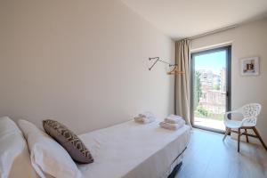 a white bedroom with a bed and a large window at Flateli- Plaça Catalunya 2-1 in Girona