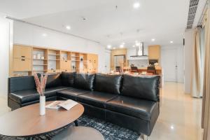 a living room with a black leather couch and a table at Karaton by Kozystay - Paskal in Bandung