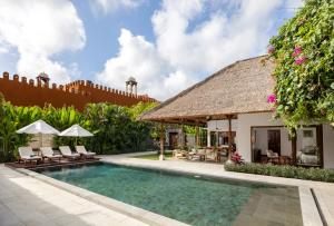 a pool at a villa with a thatch roof at Impiana Private Villas Seminyak in Seminyak
