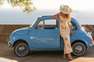 a woman is standing next to a blue car at Il Barilotto in Positano