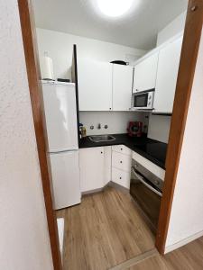 a small kitchen with white cabinets and a refrigerator at Precioso Duplex en Cala Salionç Tossa de Mar in Girona