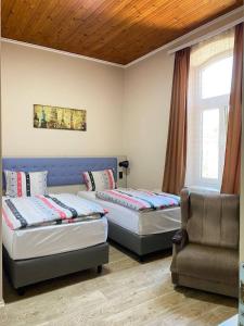 a room with two beds and a chair in it at Vila Alex in Vrnjačka Banja