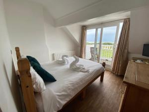 a bedroom with a bed with white sheets and a large window at The Grand Hotel in Skegness