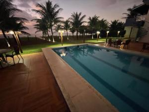 a swimming pool at night with palm trees at Casas da Geo Itacimirim - Frentemar - Pé na Areia - 03 suítes in Camacari +33 photos