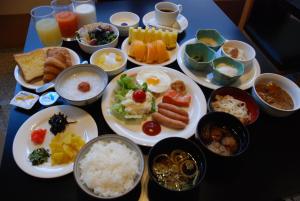 a table with plates of food and bowls of food at Albert Hotel Akita in Akita