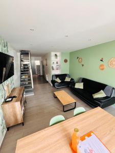 sala de estar con sofás negros y mesa en La Maison du Bastion - Gravelines centre, en Gravelines