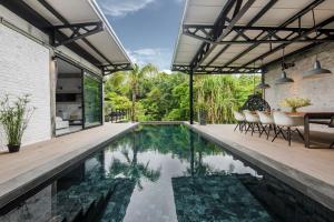 an infinity pool in a house with chairs and a table at Joana Pool Loft 17 in Thalang