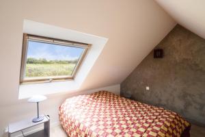 une chambre mansardée avec un lit et une fenêtre dans l'établissement 1km de la plage, maison de charme pour 6, à Plovan