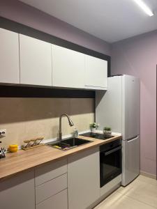 a kitchen with white cabinets and a sink and a refrigerator at Villa Passage in Ohrid