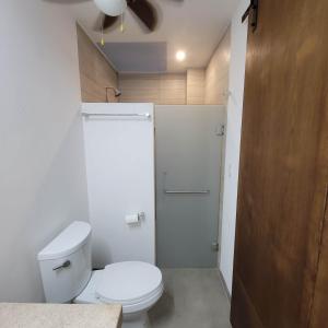 ein Badezimmer mit weißer Toilette und Dusche in der Unterkunft Casa Frida in Santa María Huatulco