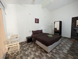 een slaapkamer met een bed, een tafel en een spiegel bij Vinsons Cottages in Colva