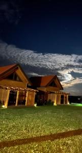 a large building with a grass field in front of it at Leniwe Chaty in Szklarnia