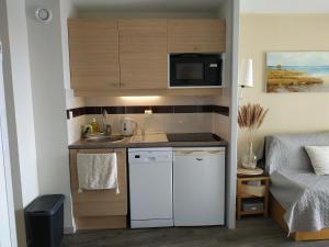 a small kitchen with a sink and a microwave at La Perle de l'Océan, à deux pas de la mer sans route à traverser, parking privé, piscine in Arzon