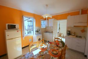 a kitchen with a table and a kitchen with orange walls at Dell' Oca in Cissano