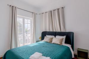 a bedroom with a bed with a green comforter and a window at Alojamento Local Coruche Erra in Coruche