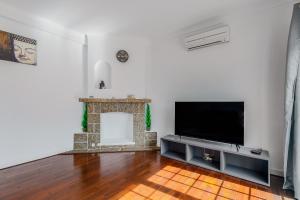 a living room with a television and a fireplace at Alojamento Local Coruche Erra in Coruche