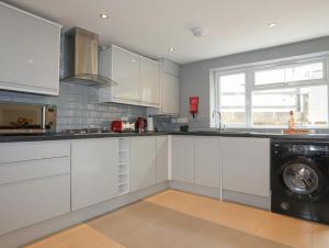 カーナーヴォンにある43 Hyfrydle Roadのキッチン(白いキャビネット、洗濯機、乾燥機付)