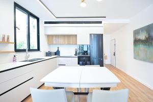 Una cocina blanca con una mesa y sillas blancas. en Elegance 3 BR in Gordon Beach by HolyGuest, en Tel Aviv