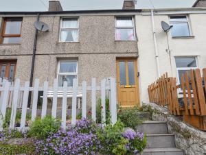 a white fence in front of a house with flowers at 42 Hyfrydle Road in Caernarfon