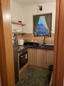 a kitchen with a sink and a refrigerator and a window at Vikendica Paša in Pale