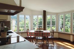 a kitchen with a table and chairs and windows at Residenza Nemus Olea Mare e Montagna Casa Vacanze in Graveglia