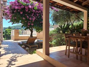 a patio with a table and a tree with purple flowers at Villa Blue Promenade in Dubrovnik