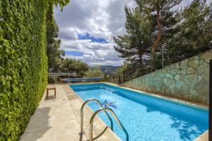 ein Swimmingpool mit einer Steinmauer neben einer Hecke in der Unterkunft Casa Serrania in Collado Mediano