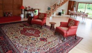 a living room with red chairs and a rug at Le Moulin des hirondelles in Pluvigner