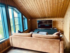 a living room with a couch in a room with windows at New, cozy, and comfortable cabin in Geilo in Flatåker