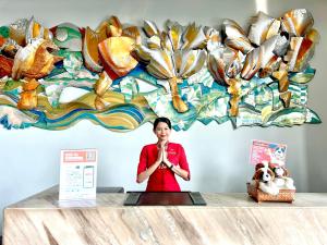 a woman is standing in front of a counter with a sign at Swiss-Belinn Airport Surabaya in Sidoarjo