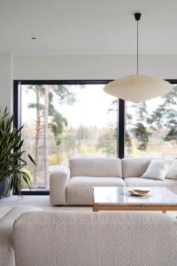 a living room with a white couch and a large window at Unique lakehouse Villa Valo in Hollola