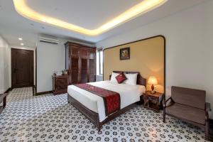 a bedroom with a large white bed and a desk at Le Maison Tam Coc Boutique Hotel in Ninh Binh