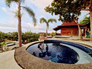 a pool in the middle of a yard with palm trees at Villa Bakso Mentigi in Teluknarat
