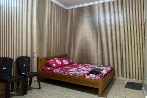 a bedroom with a bed and two black chairs at Family 24 Hotel near Pantai Cipatujah in Cipatujah
