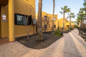 un edificio giallo con palme accanto a un marciapiede di B-Rent Perla de Mar a Corralejo