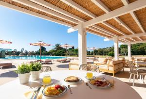 a table with food and drinks on a patio with a pool at Is Molas Resort in Pula