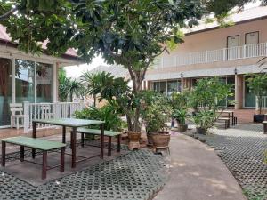 a table and benches in front of a building with trees at Sea Beach Koh Larn 1 in Ko Larn