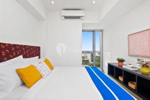 - une chambre blanche dotée d'un grand lit avec des oreillers jaunes et bleus dans l'établissement Aura by Kozystay - BSD, à Tangerang 11 autres photos